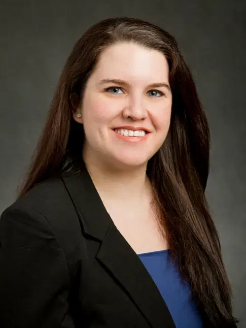 Professional portrait of Dr. Michelle P. Flores wearing a black blazer and blue top