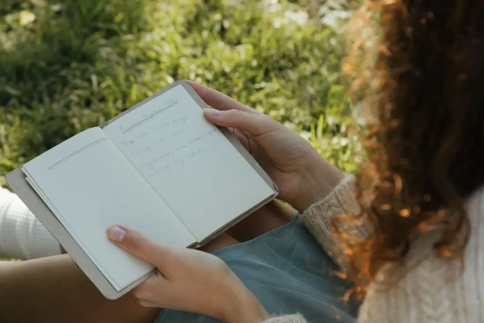 Person holding a notebook while sitting outdoors